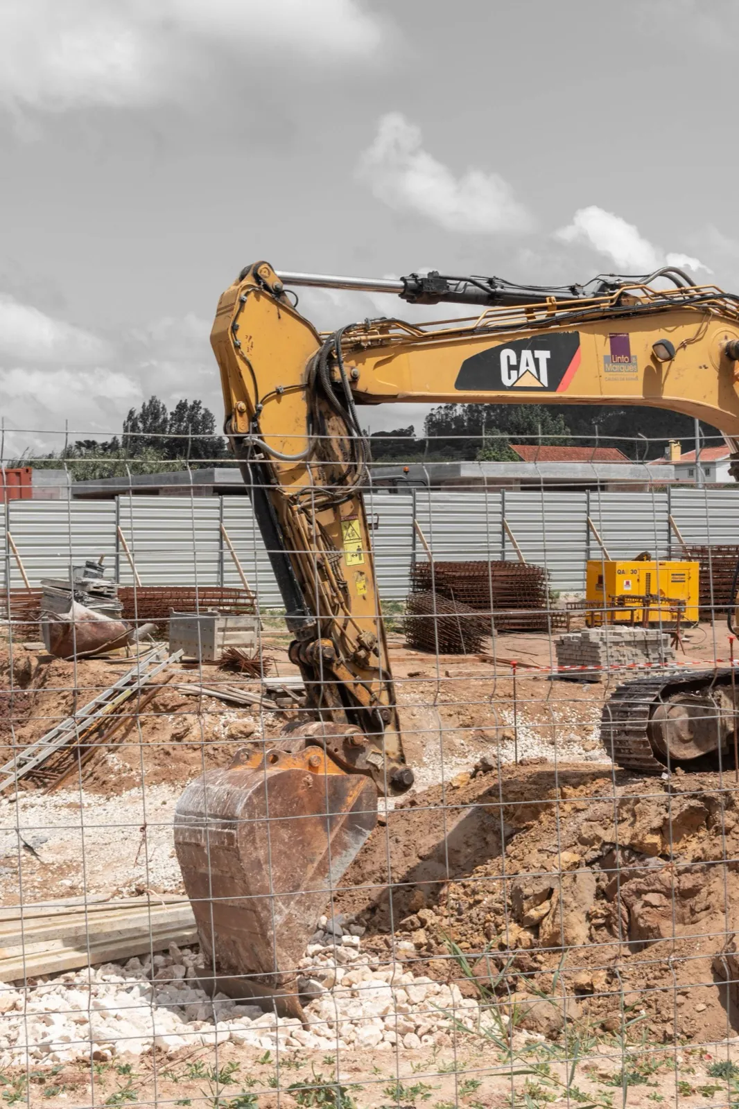 An excavator working over a dug out foundation with fresh block walls going up.